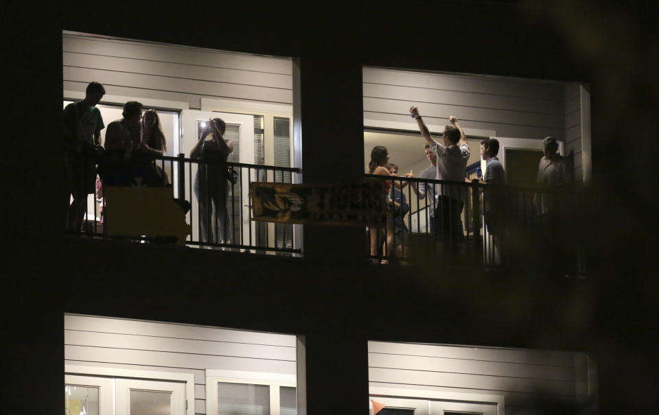 FILE - In this Sept. 1, 2020 file photo, partiers congregate on the balcony of a downtown apartment in Columbia, Mo., near the University of Missouri campus. College towns across the U.S. have emerged as coronavirus hot spots in recent weeks as schools struggle to contain the virus. In many cases, surges have been blamed on off-campus parties. The University of Missouri announced this week that it expelled two students and suspended three others for violating rules meant to slow the virus’s spread. (Dan Shular/Missourian via AP, File)