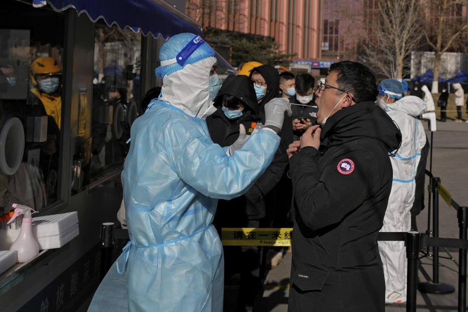 CORRECTS TO SWAB, NOT NASAL SWAB - A man gets a swab for the COVID-19 test to meet traveling requirements at a mobile coronavirus testing facility outside a commercial office buildings in Beijing, Sunday, Jan. 16, 2022. Beijing has reported its first local omicron infection, according to state media, weeks before the Winter Olympic Games are due to start. (AP Photo/Andy Wong)