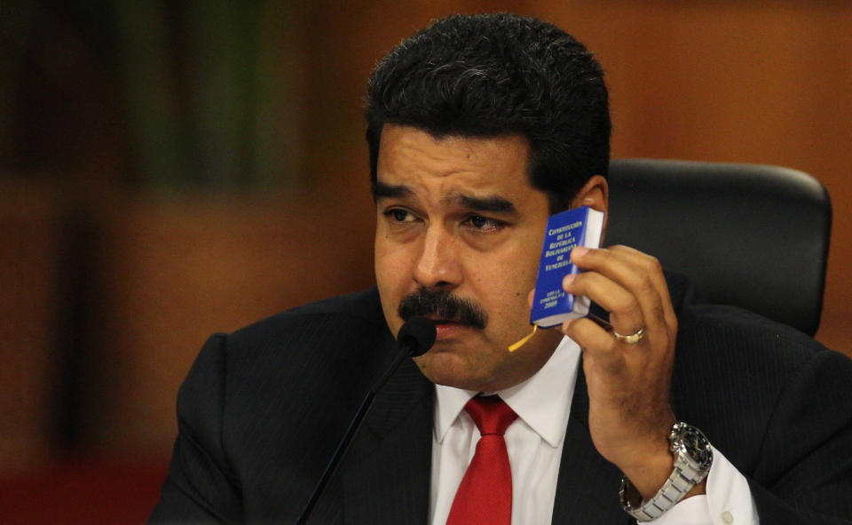 Venezuela's President Nicolas Maduro holds up a small copy on the constitution during a meeting with leaders of the opposition at Miraflores presidential palace in Caracas, Venezuela, Thursday, April 10, 2014. Maduro's opponents blame his government for destroying the oil-rich economy and stamping out dissent. Meanwhile Maduro claims he's the target of U.S.-backed coup attempt. (AP Photo/Fernando Llano)