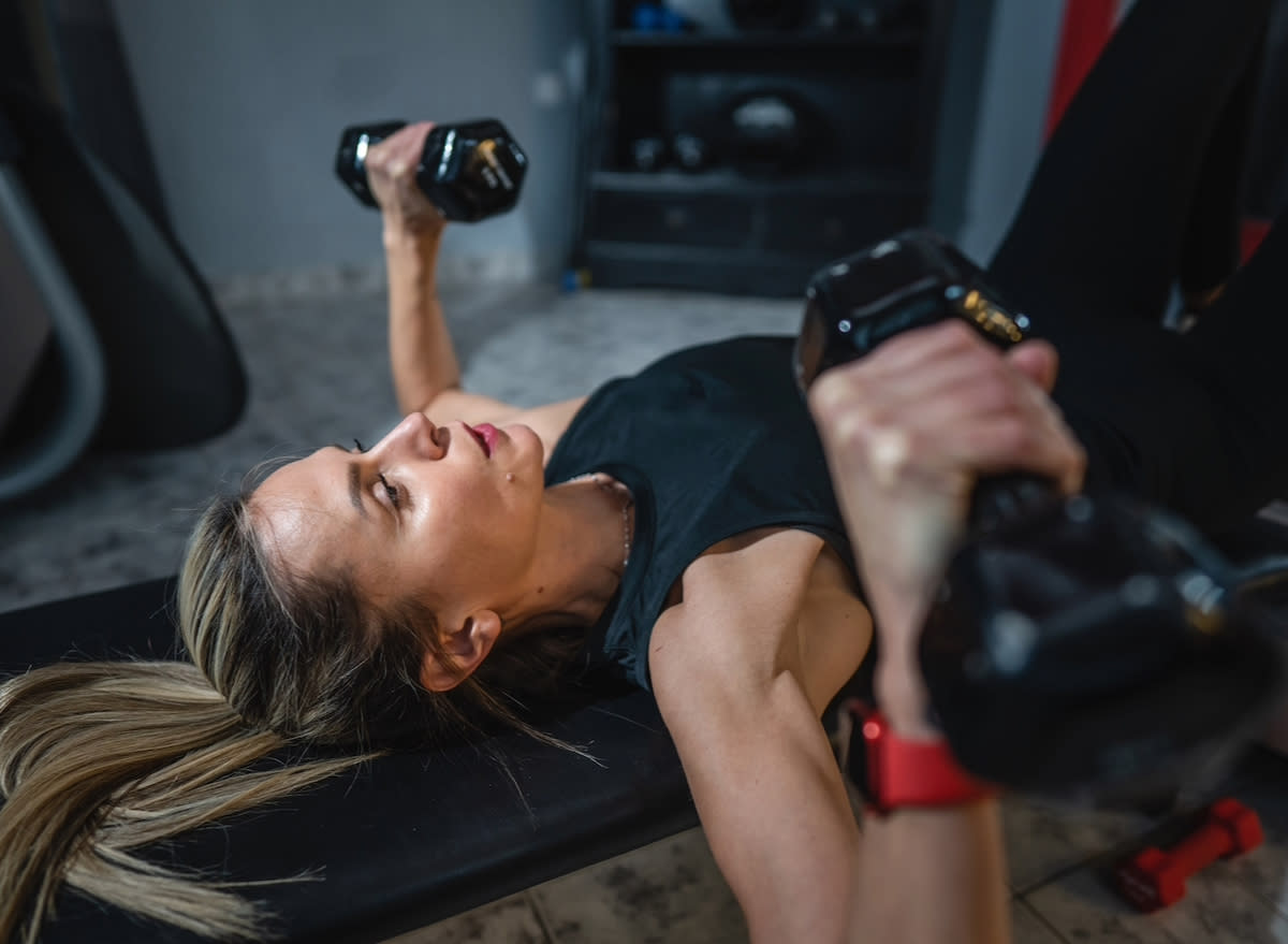 woman doing dumbbell bench press, concept of strength workouts for flabby arms