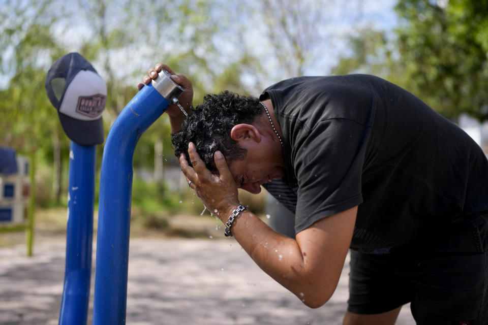 Un hombre se echa agua de una fuente en la cabeza para refrescarse en un parque de Buenos Aires, Argentina, el martes 14 de marzo de 2023. (AP Foto/Natacha Pisarenko)