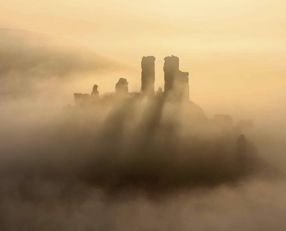 By Marc Bauer: Corfe Castle silhouetted in mist, Dorset, England.