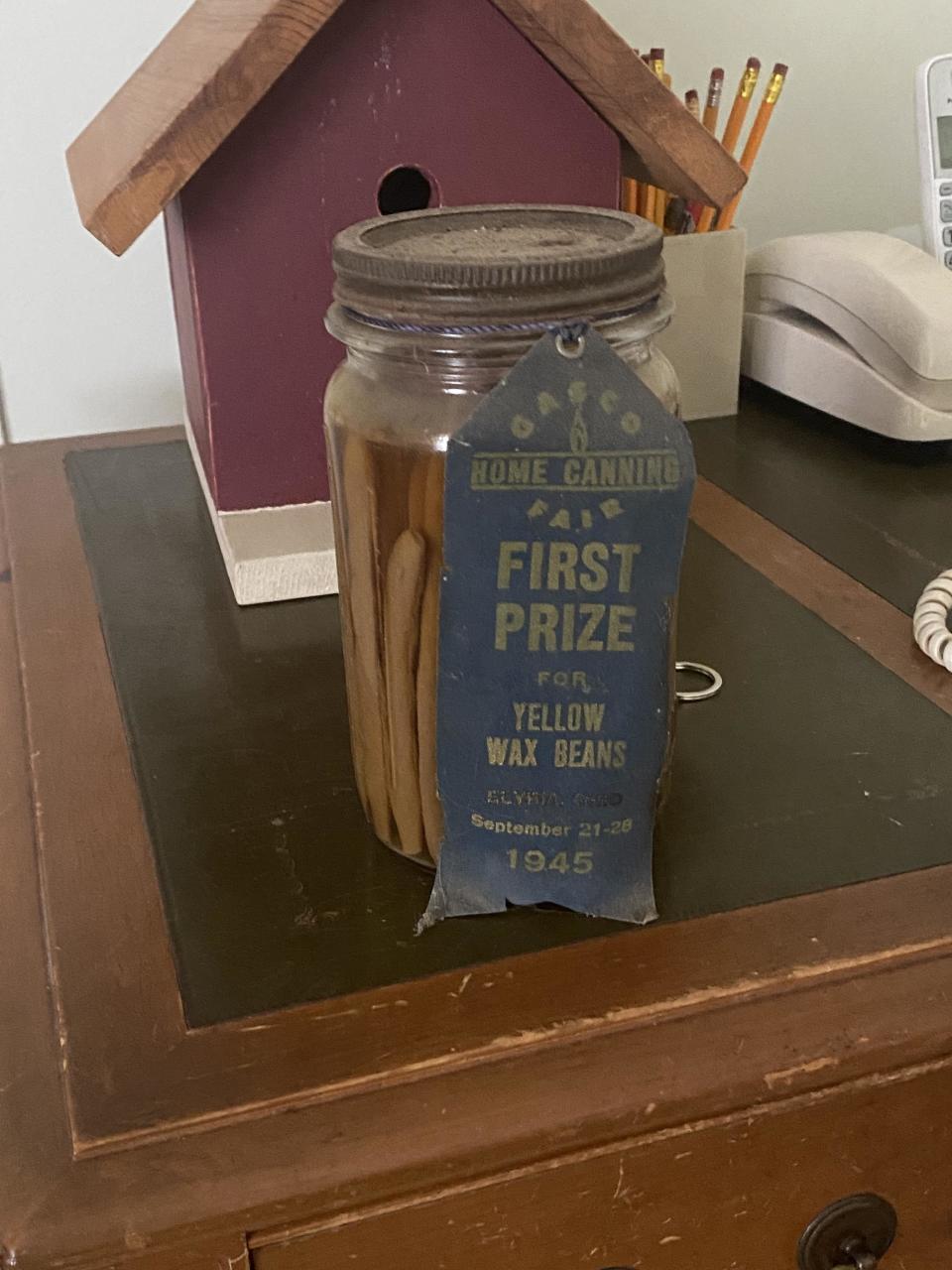 Jar of yellow wax beans with a 'First Prize' ribbon from a 1945 canning fair on a wooden surface