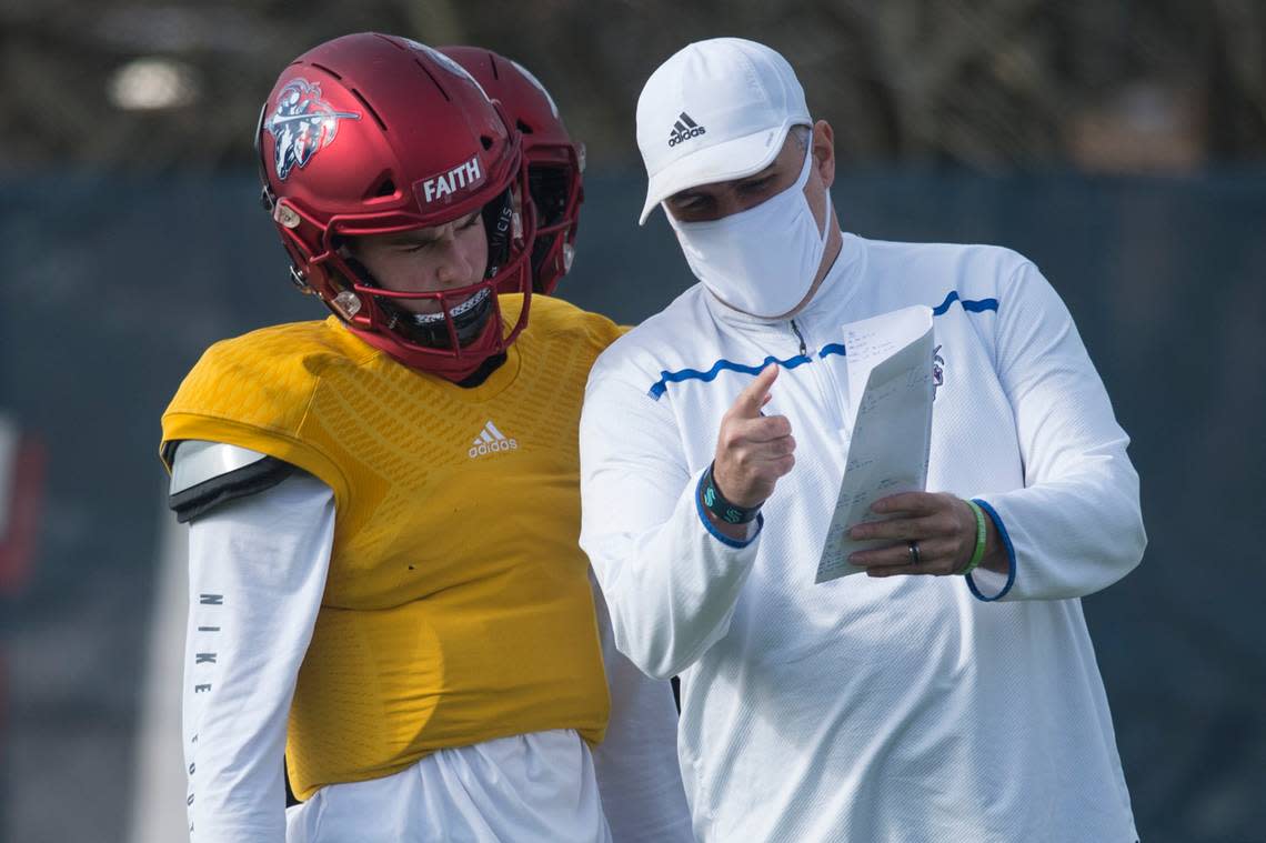 Kennedy Catholic High School quarterback Sam Huard and coach Sheldon Cross go over a play during practice on Tuesday, March 23, 2021 at Kennedy Catholic High School in Burien, Wash.