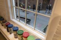 FILE - People line up outside a COVID-19 walk-in testing site as seen through a shop window, Sunday, Dec. 5, 2021, in Cambridge, Mass. Even as the U.S. reaches a COVID-19 milestone of roughly 200 million fully-vaccinated people, infections and hospitalizations are spiking, including in highly-vaccinated pockets of the country like New England. (AP Photo/Michael Dwyer, File)