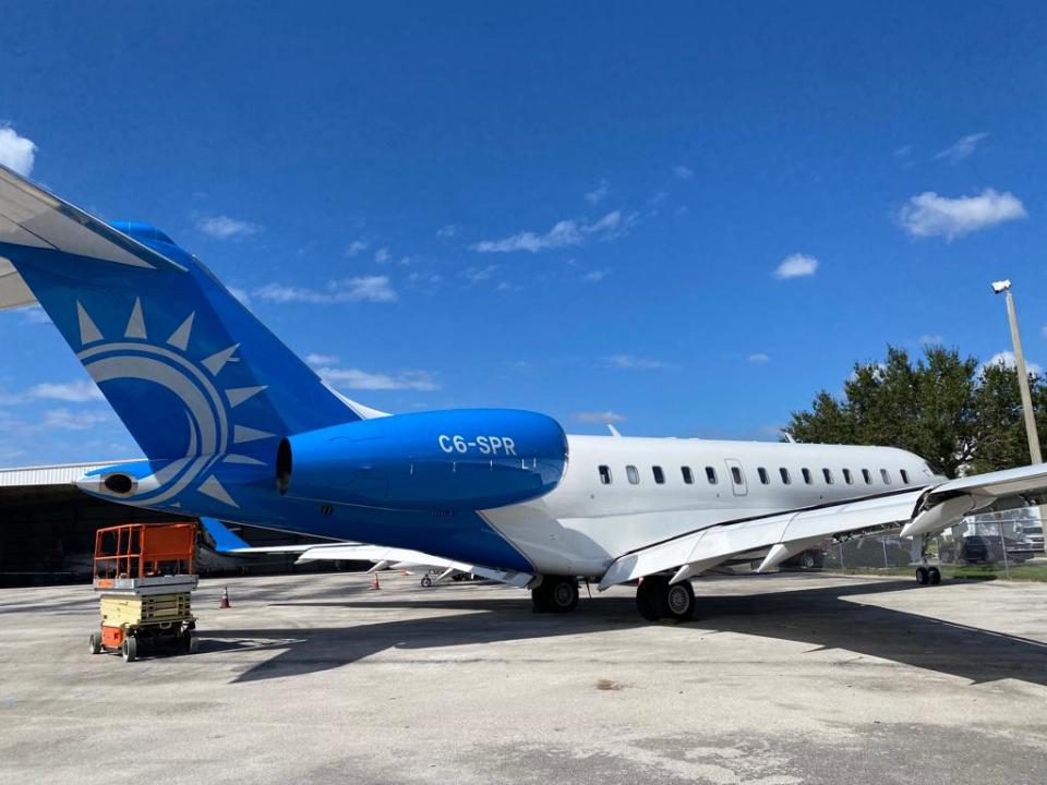 A Bombardier Global 5000 jet on the tarmac in a white livery with blue tail and engine, tail number C6-SPR