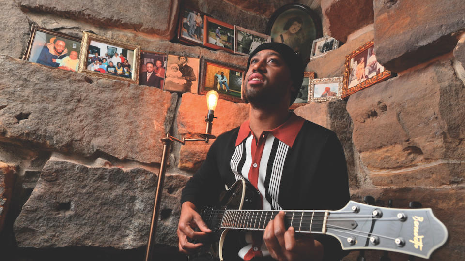 Dan Wilson plays guitar surrounded by photos of his relatives and loved ones