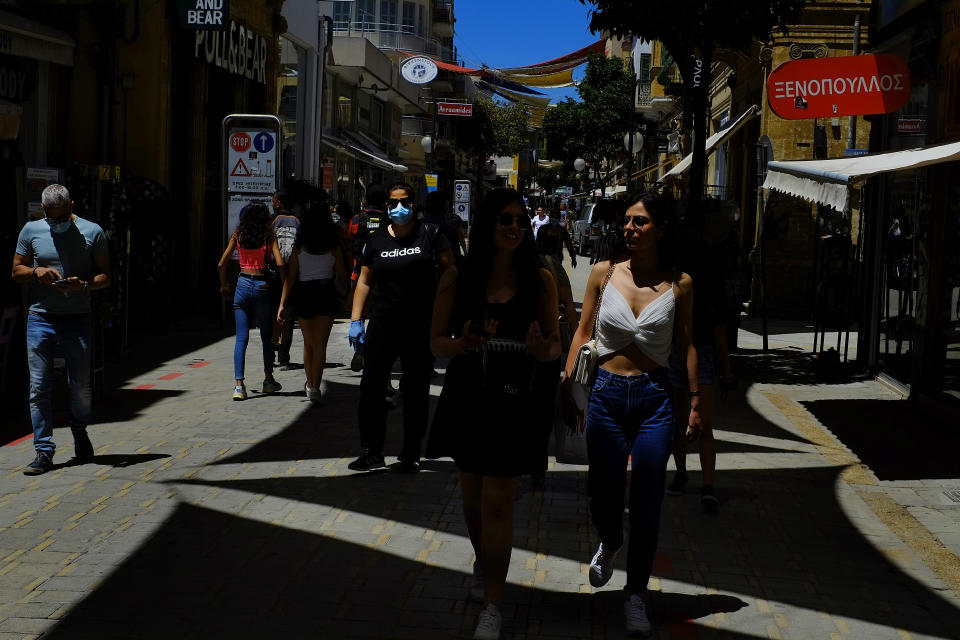 CORRECTING DAY TO MONDAY - People walk on Ledra street a main shopping street in Nicosia, Cyprus, Monday May 25, 2020. Cyprus took a major step toward a return to normality on Monday when most restrictions of a two month-long stay-at-home order were lifted, allowing primary school kids to return to classes and hair salons and outdoor cafeterias to re-open. (AP Photo/Petros Karadjias)