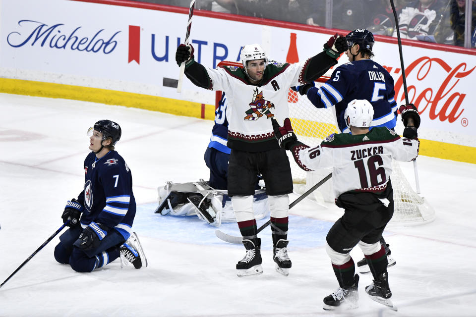 Arizona Coyotes center Nick Schmaltz (8) celebrates his goal on Winnipeg Jets goaltender Connor Hellebuyck (37) with teammate Jason Zucker (16) during the first period of an NHL hockey game in Winnipeg, Manitoba on Sunday, Feb. 25, 2024. (Fred Greenslade/The Canadian Press via AP)
