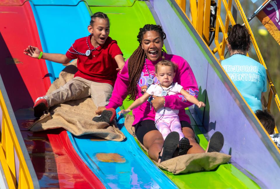 Antonio Young, left, Tubtub Young, center, and Nyla young, right, hit the slide during Special Kids Day at the 2023 West Side Nut Club Fall Festival in Evansville, Ind., Tuesday, Oct. 3, 2023.