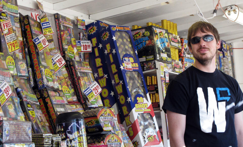 In this Thursday, June 28, 2012 photo, TNT Fireworks employee Casey Hern stands in front of fireworks for sale, in Helena, Mont. Montana officials have urged people not to shoot fireworks while extreme wildfire conditions exist. (AP Photo/Matt Volz)