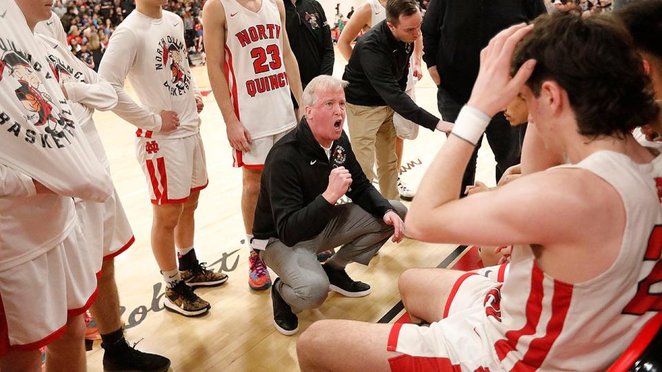 North Quincy coach Kevin Barrett fires up his players during a time out during an MIAA tournament game against Walpole on Wednesday, March 9, 2022.