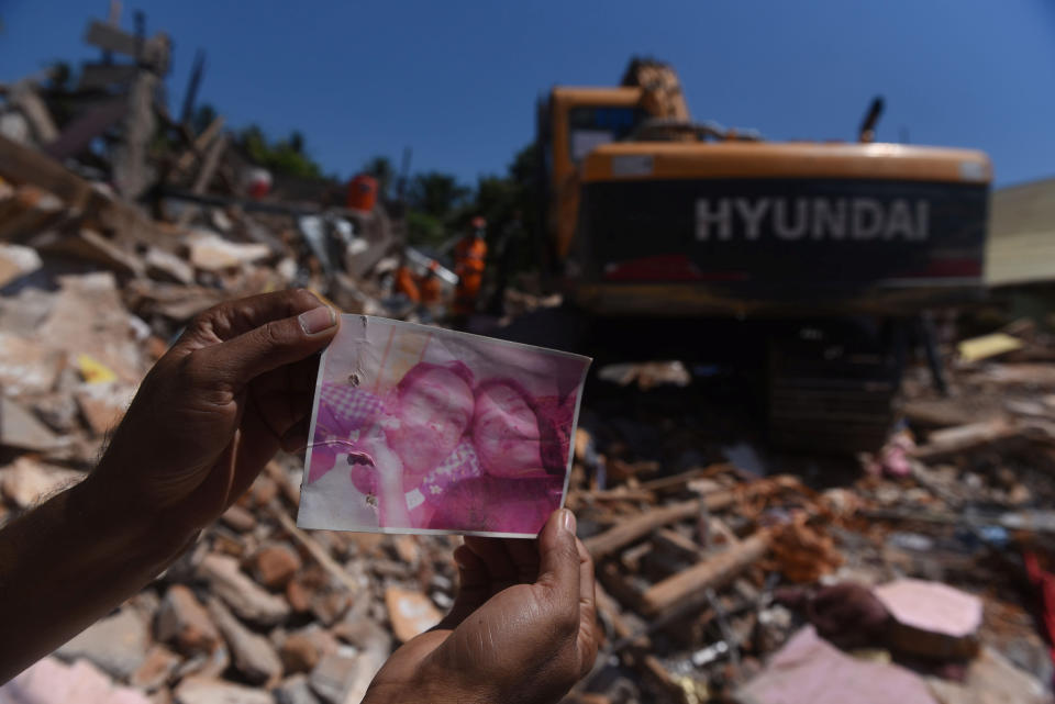 <p>A resident shows a photo of missing victims believed to be trapped inside a collapsed building, as rescue workers continue searching after Sunday’s earthquake in Pemenang, North Lombok, Indonesia, Aug. 8, 2018. (Photo: Antara Foto/Zabur Karuru via Reuters) </p>