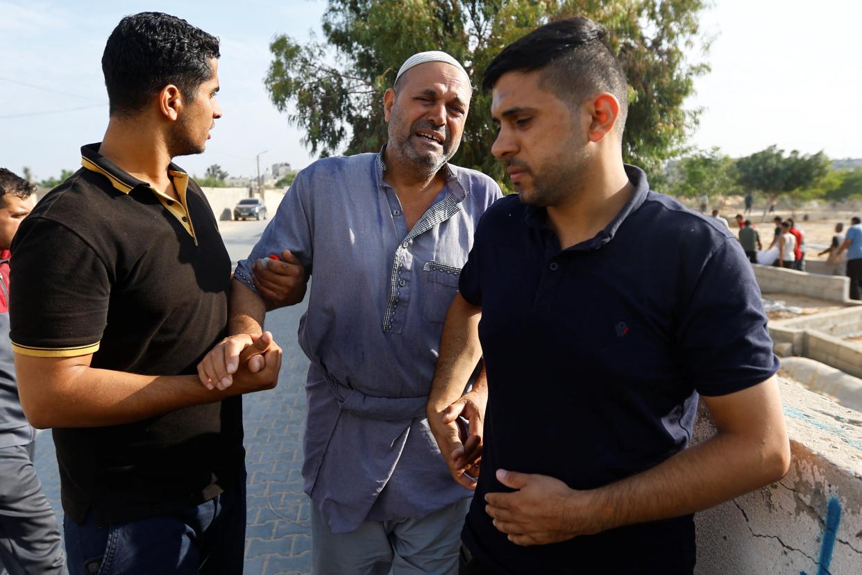 Three men mourn at a funeral of Palestinians killed in Israeli air strikes (REUTERS)