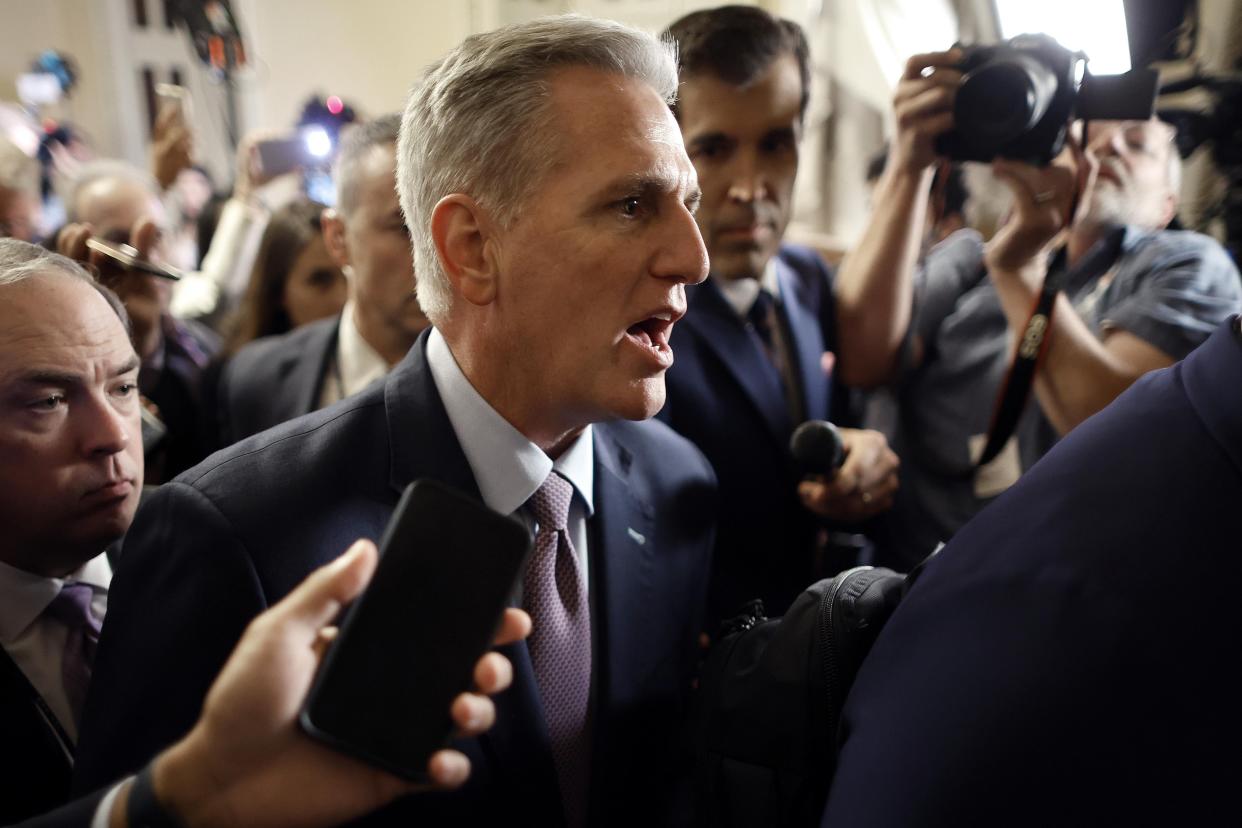 Speaker of the House Kevin McCarthy  is surrounded by staff, security, and journalists as he walks to the House Chamber ahead of a vote.