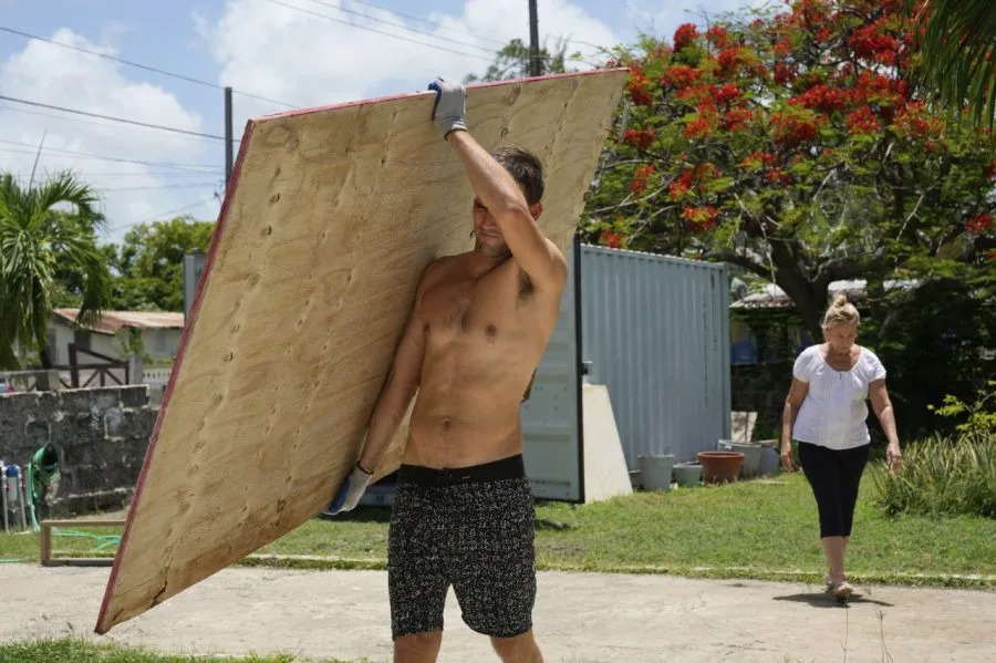 A resident carries wood to cover his house’s windows in preparation for Hurricane Beryl, in Bridgetown, Barbados, Sunday, June 30, 2024. (AP Photo/Ramon Espinosa)