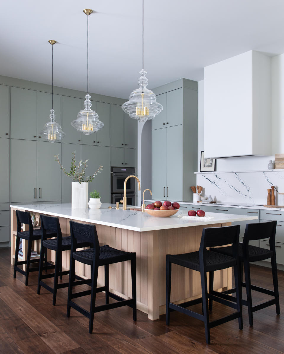 kitchen with oak island, white marble top, and sage tall cabinets