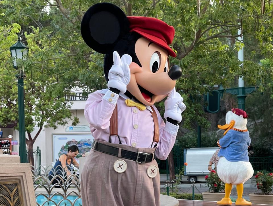 mickey mouse posing for photos at disneyland
