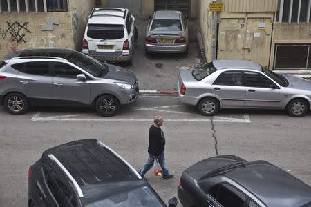 A man walks past parked cars on a street in Tel Aviv February 18, 2015. REUTERS/Nir Elias