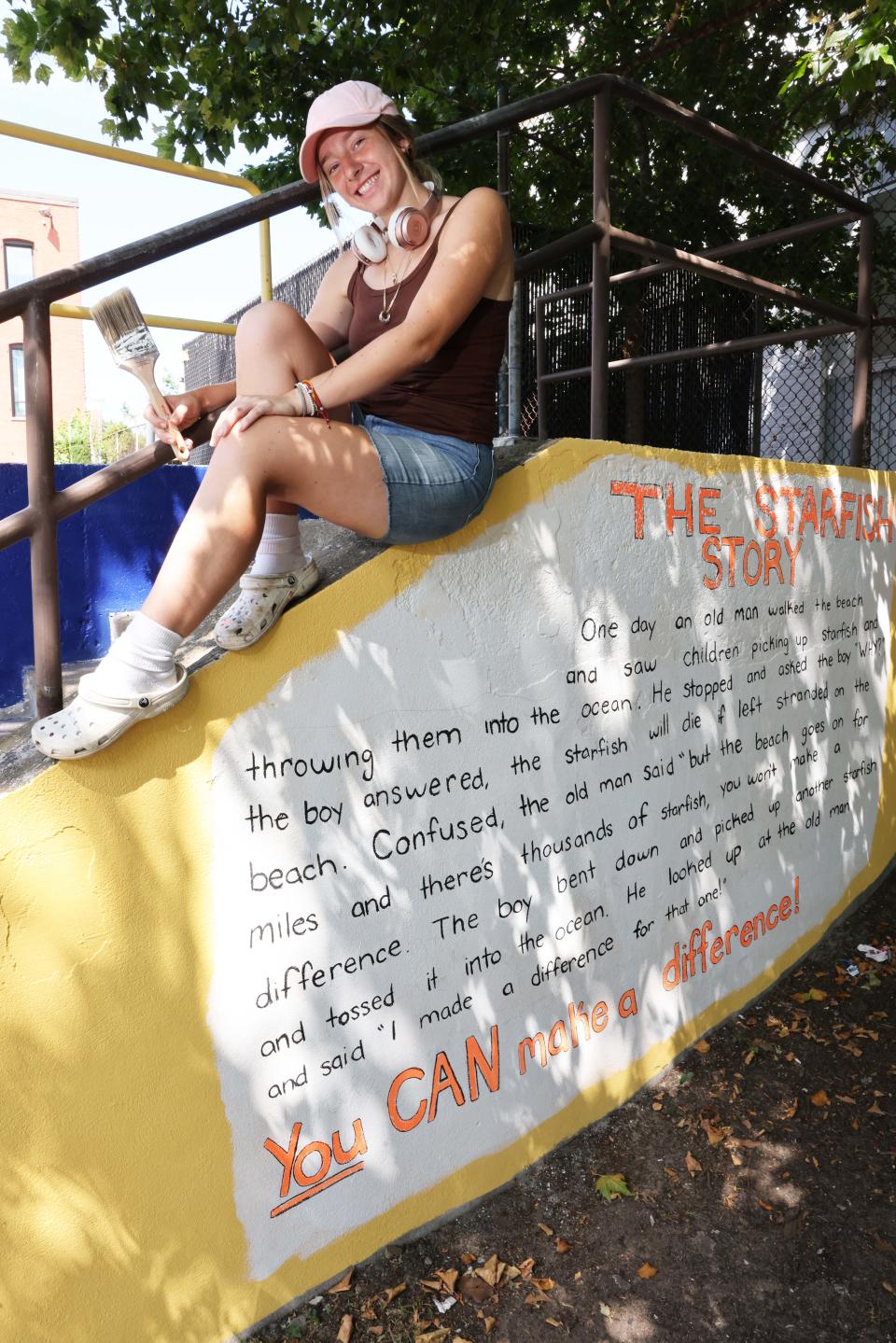 Jessica Picanzo, 22, of Brockton, takes a break from painting a mural called "Make A Difference" outside Brockton Community Access on Friday, July 29, 2022.
