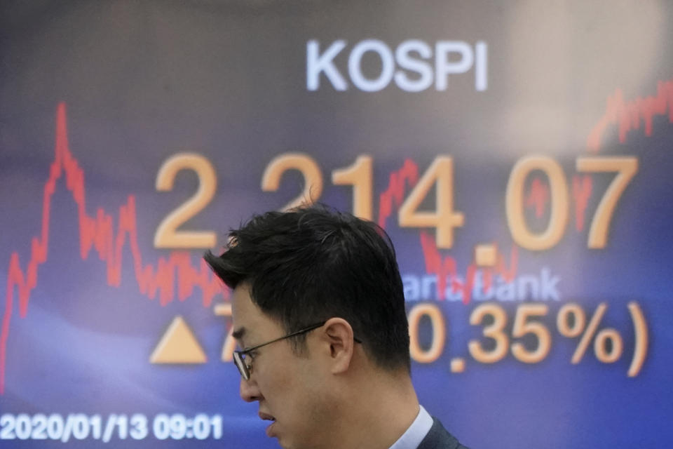 A currency trader walks by the screen showing the Korea Composite Stock Price Index (KOSPI) at the foreign exchange dealing room in Seoul, South Korea, Monday, Jan. 13, 2020. Asian stocks have risen as investors shrug off weaker-than-expected American jobs data and look ahead to the signing of a U.S.-China trade deal. Benchmarks in Shanghai, Hong Kong and Southeast Asia all advanced. (AP Photo/Lee Jin-man)