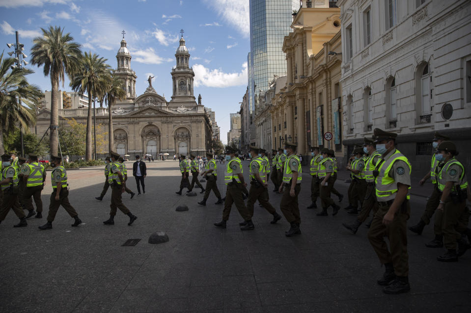 Police officers arrive at a meeting point in the Plaza de Armas to start a day of checking people's transit permissions as part of lockdown measures to contain the spread of COVID-19, in Santiago, Chile, Wednesday, April 21, 2021. (AP Photo/Esteban Felix)