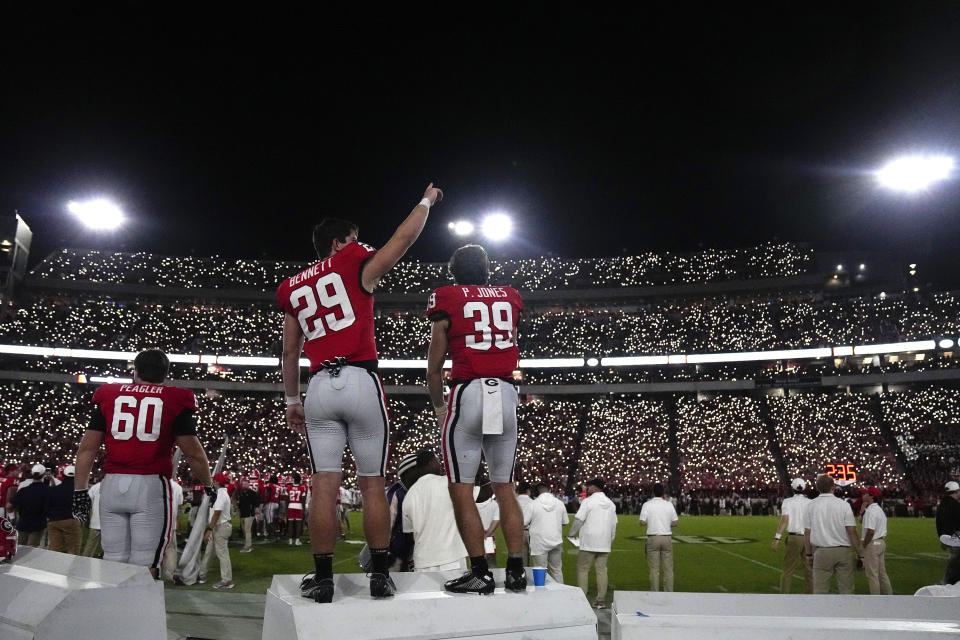 Georgia wide receivers Luke Bennett (29) and Parker Jones (39) stand on the bench as Dooley Field at Sanford Stadium is illuminated by cellular phones to mark the start of the fourth quarter of an NCAA college football game against Tennessee-Martin, Saturday, Sept. 2, 2023, in Athens, Ga. (AP Photo/John Bazemore)