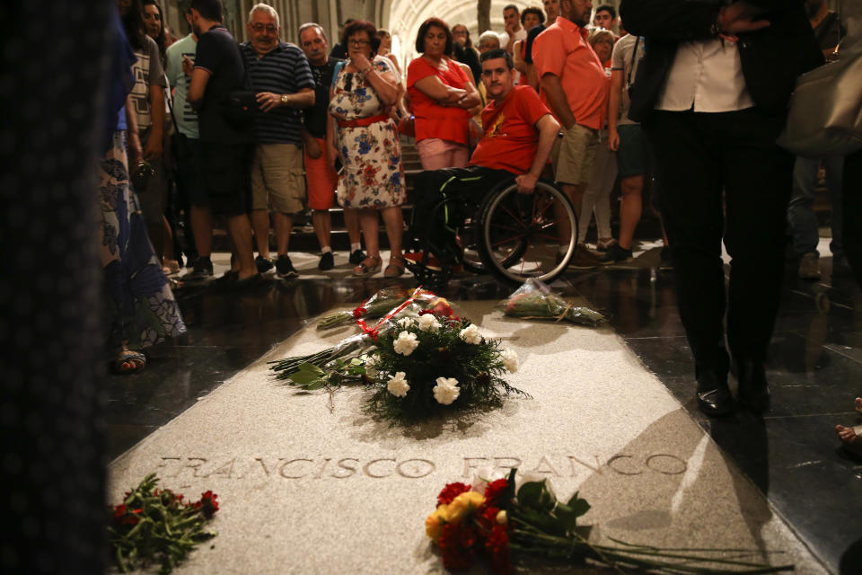 People stand around the tomb of former Spanish dictator Francisco Franco inside the basilica at the the Valley of the Fallen monument near El Escorial, outside Madrid, Friday, Aug. 24, 2018. Spain's center-left government has approved legal amendments that it says will ensure the remains of former dictator Gen. Francisco Franco can soon be dug up and removed from a controversial mausoleum. (AP Photo/Andrea Comas)