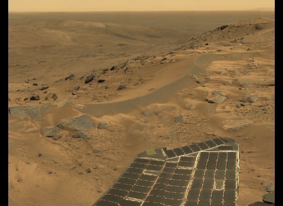 A view from high in the Columbia Hills, looking over the rover's right solar panel "wing" and  down into the Tennessee Valley.  Just like on Earth, hills and ridges on Mars are windy places.The wind creates sand dunes and scours rocks; sometimes it also cleans the dust off the rover's solar panels!    <em>  Spirit rover Pancam image, mission sol 582 (August 23, 2005).  From "Postcards from Mars" by Jim Bell; Photo credit: NASA/JPL/Cornell University  </em>