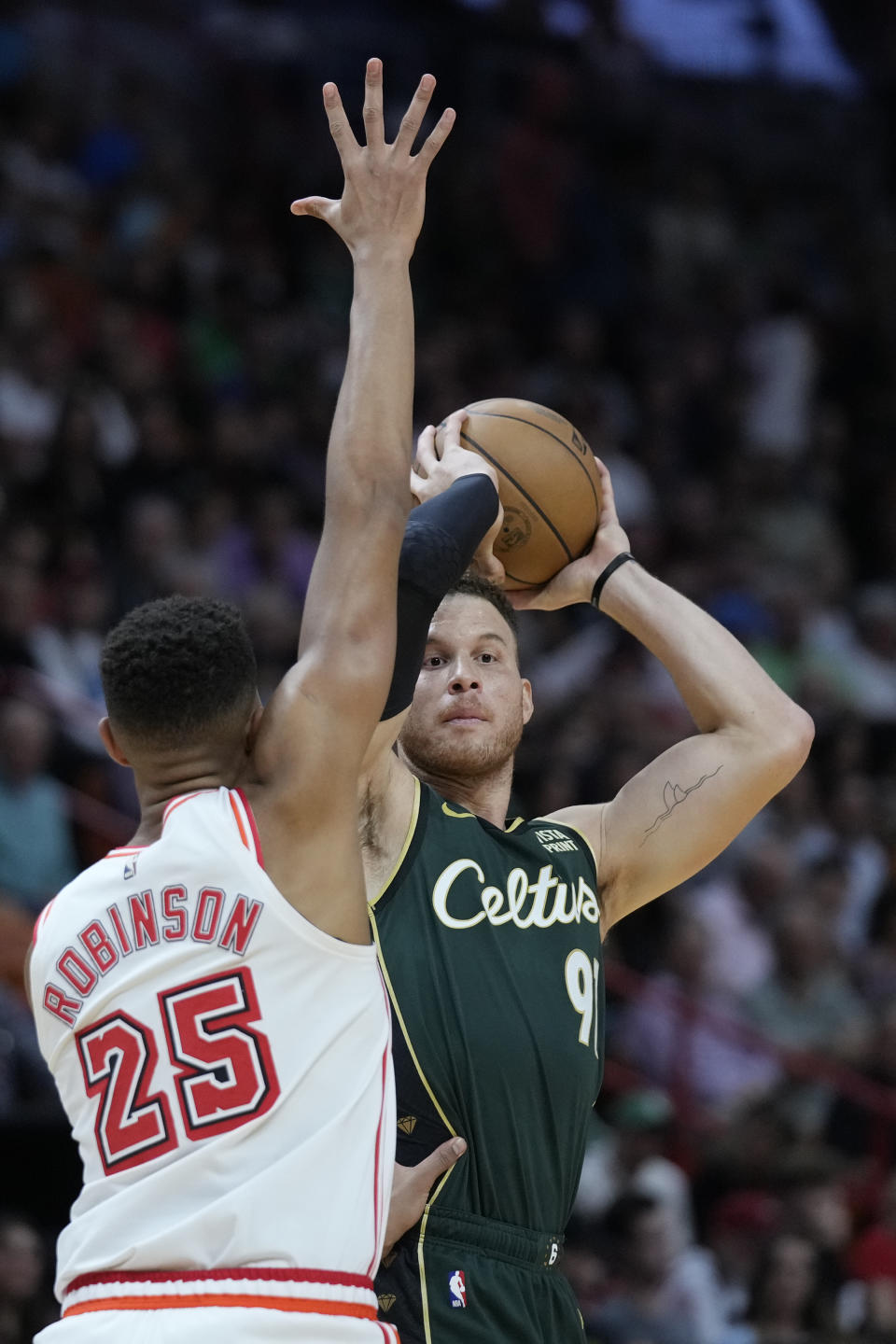 Boston Celtics forward Blake Griffin, rear, looks for an open teammate past Miami Heat center Orlando Robinson (25) during the first half of an NBA basketball game, Tuesday, Jan. 24, 2023, in Miami. (AP Photo/Wilfredo Lee)