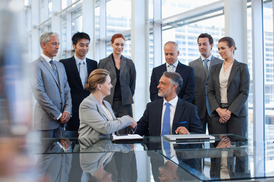 Business people shaking hands in conference room.