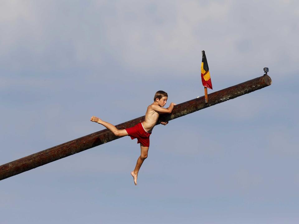 child on pole covered in grease, hanging on 