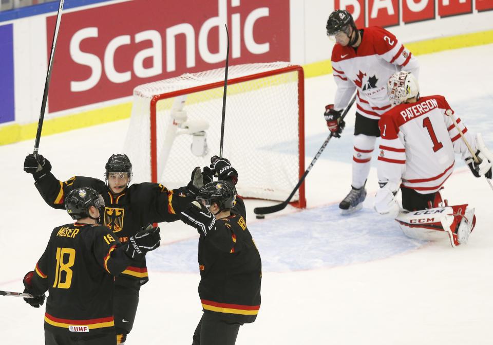 Germany's Janik Moser (L) celebrates his goal on Canada's goalie Jake Paterson (R) with teammates Kai Herpich and Dominik Kahun (2nd L) as Canada's Adam Pelech removes the puck from the net during the first period of their IIHF World Junior Championship ice hockey game in Malmo, Sweden, December 26, 2013. REUTERS/Alexander Demianchuk (SWEDEN - Tags: SPORT ICE HOCKEY)