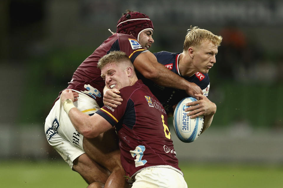 Carter Gordon of the Rebels, right, is tackled by Highlanders' defenders during their Super Rugby Pacific Round 8 match in Melbourne, Saturday, April 13, 2024. (Rob Prezioso/AAP Image via AP)