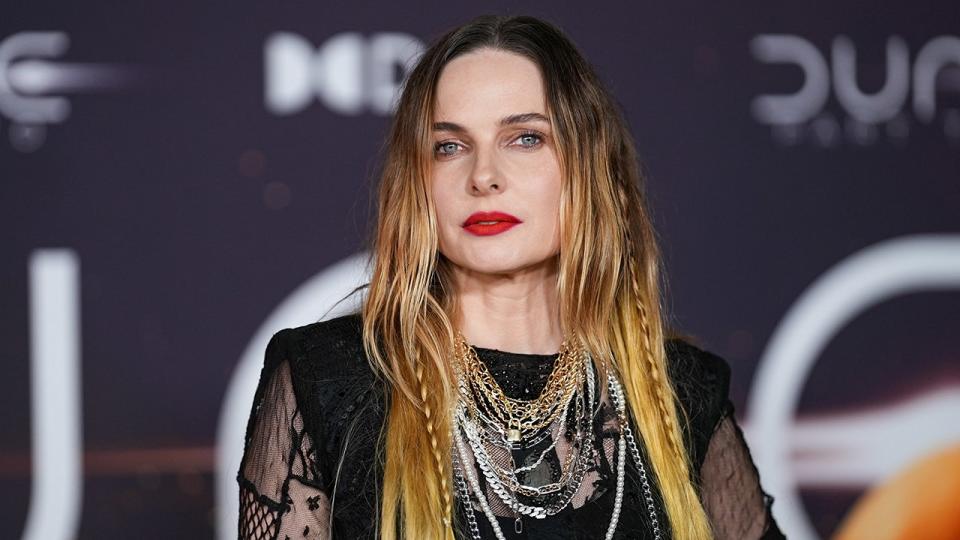 Rebecca Ferguson wearing several silver chains and a black dress with lace on the carpet