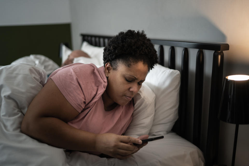 Woman in bed checking smartphone. (Getty Images)