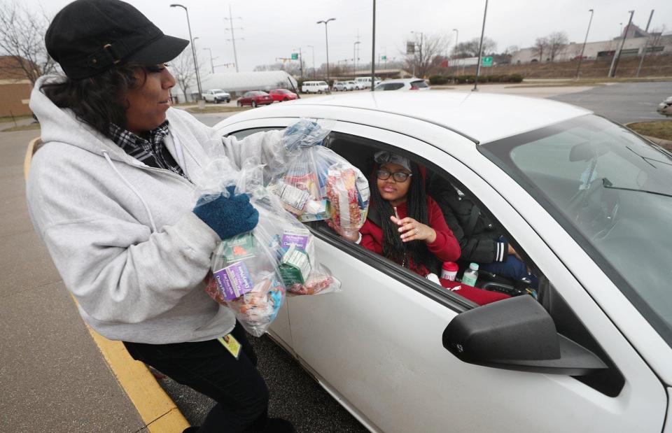Akron Public Schools plans to hand out grab-and-go bags of food during a possible teacher strike. The district already has experience after schools closed during parts of the COVID-19 pandemic. Here, Marva Roberts, hands food to Sharaylynn Gonzalez, 12, and her mom, Rhonda Davis, for their family at Helen Arnold CLC in Akron in 2020.