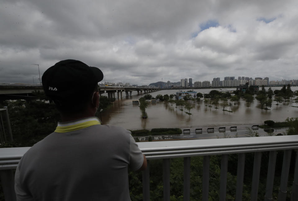 A man watches the flooded park near the Han River in Seoul, South Korea, Thursday, Aug. 6, 2020. The state-run Han River Flood Control Office issued a flood alert near a key river bridge in Seoul, the first such advisory since 2011. (AP Photo/Lee Jin-man)