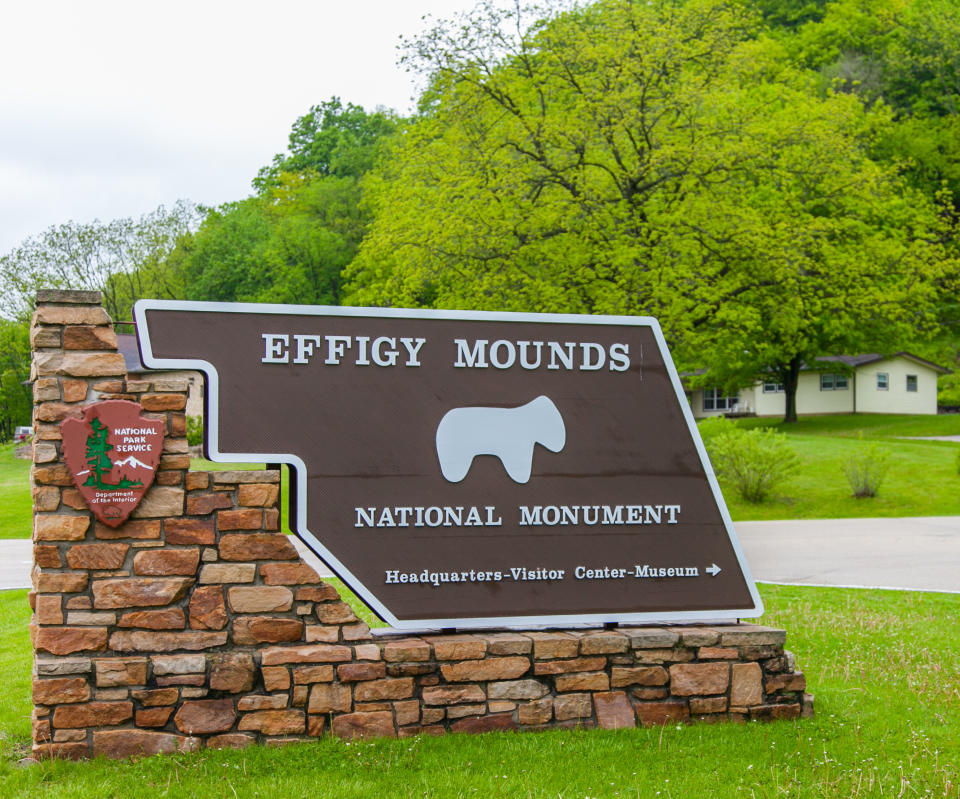 A sgn reads, "Effigy Mounds National Monument" and points in the direction of the " headquarters, visitor center, museum"