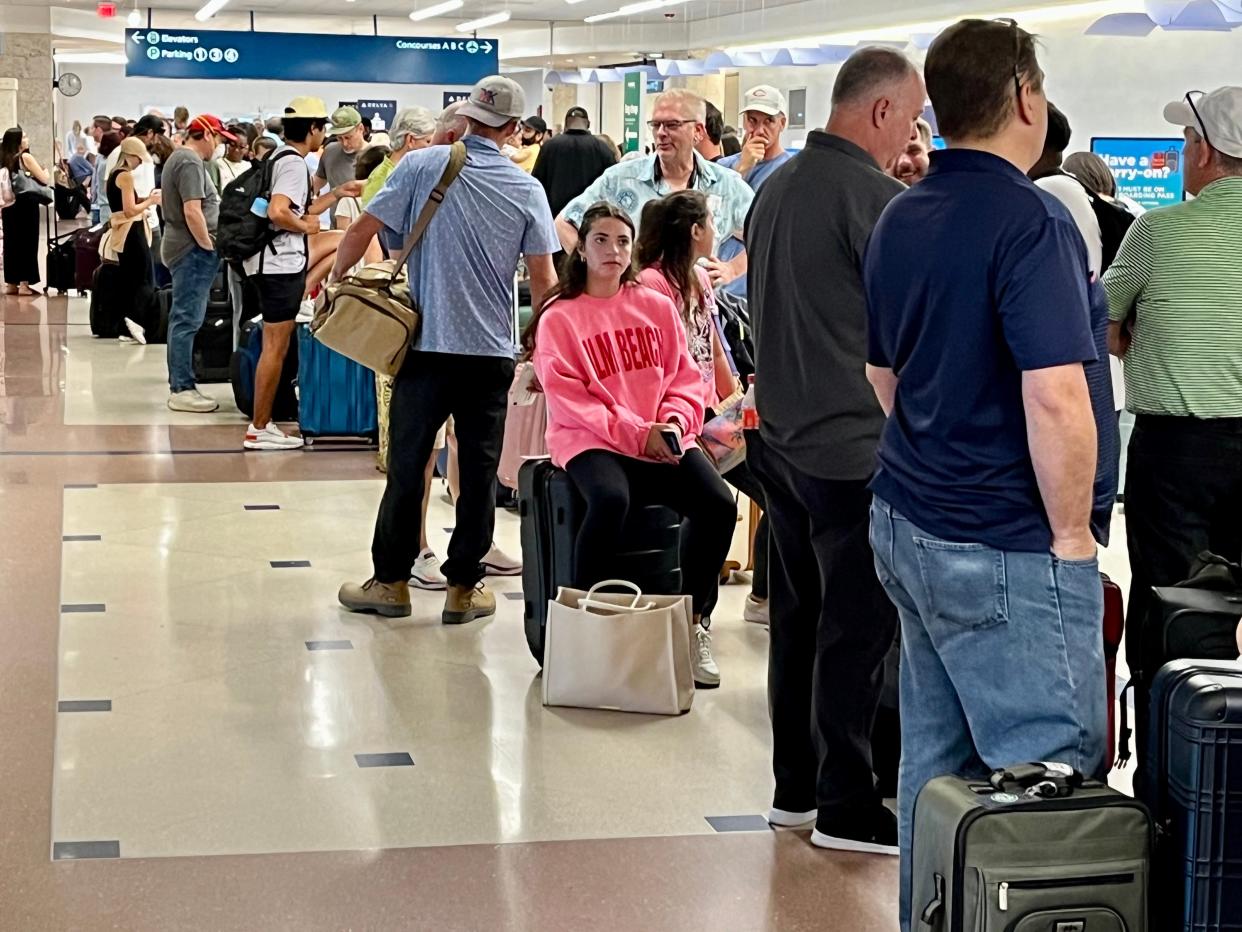 Passengers wait in line at the Delta Airlines terminal at Palm Beach International Airport on Friday, July 19, 2024. Thousands of U.S. flights were grounded Friday in a technical malfunction that paralyzed many airlines, banks and state agencies.