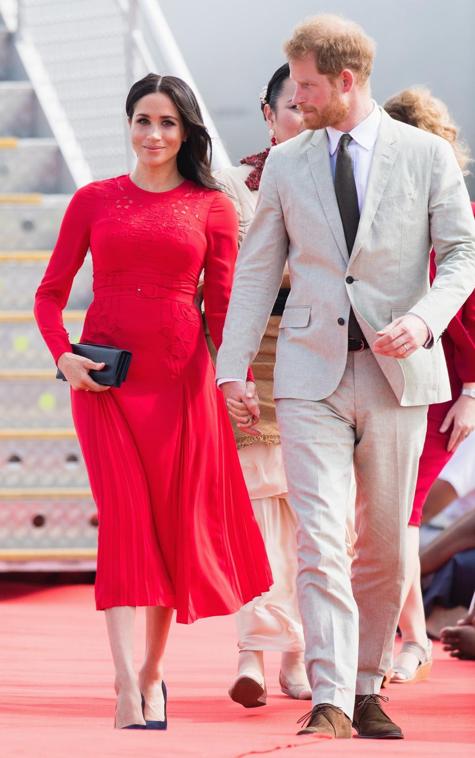 For the next leg of the royal tour, in Tonga, Markle stepped off the plane in a red Self-Portrait dress that showed off her growing baby bump.