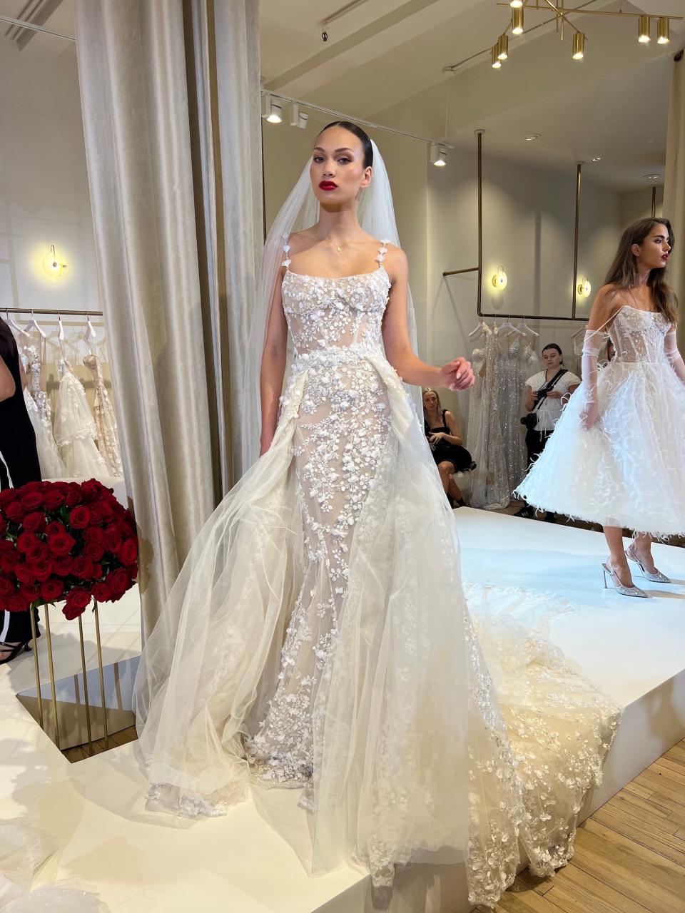 A woman poses in a wedding dress with floral applique and a tulle skirt.