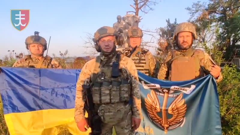 Ukrainian soldiers stand with Ukrainian flag in Urozhaine