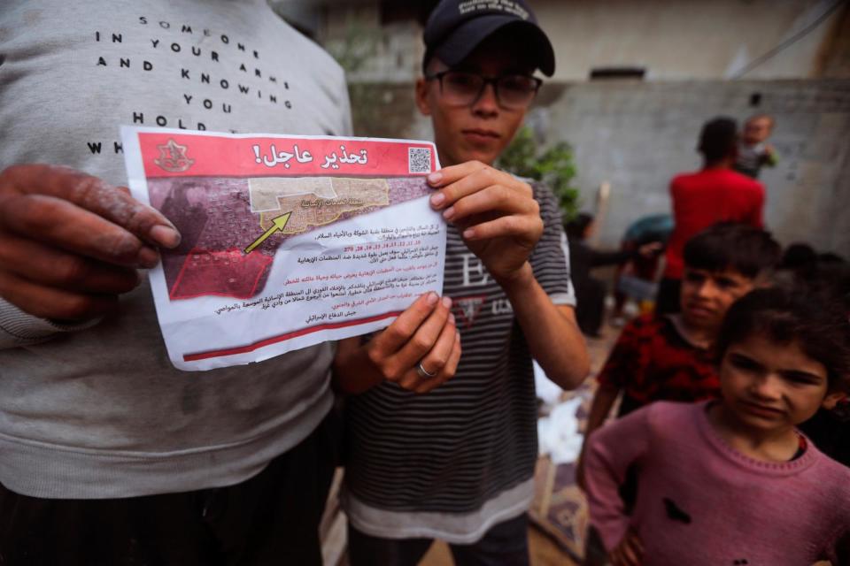 PHOTO: Palestinians hold leaflets dropped by Israeli planes calling on them to evacuate ahead of an Israeli military operation in Rafah, southern Gaza Strip, Monday, May 6, 2024. (Ismael Abu Dayyah/AP)