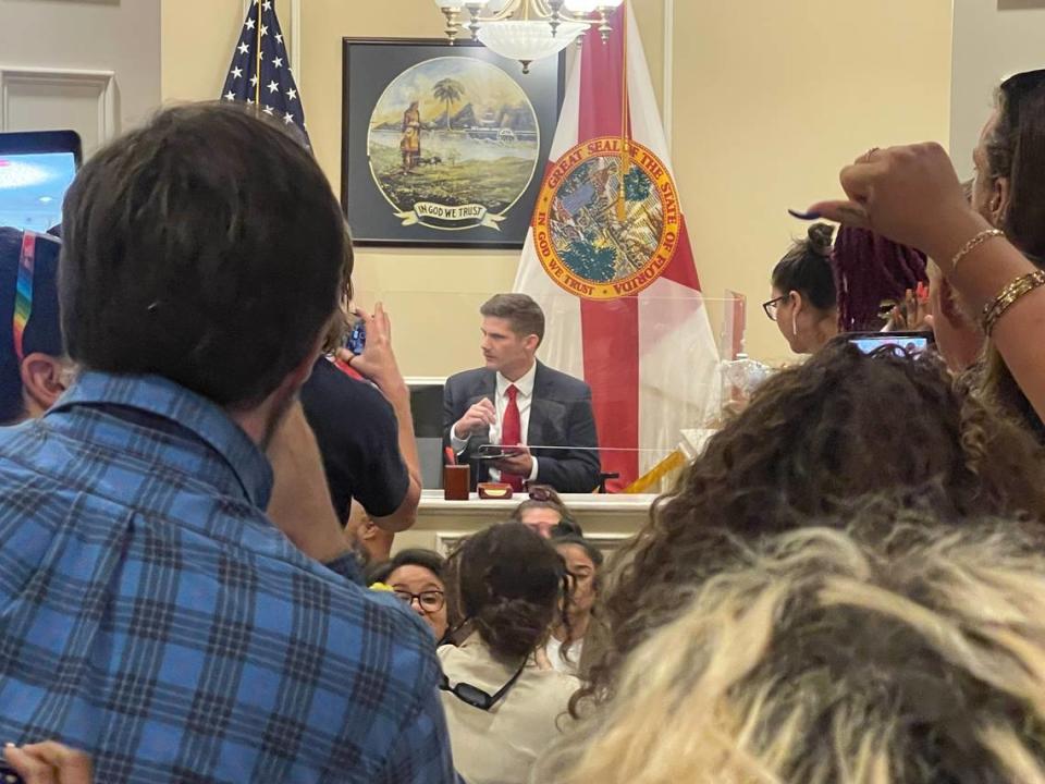 Un empleado de la oficina del gobernador Ron DeSantis comiendo pastel de chocolate mientras unas cuantas docenas de manifestantes organizaban una manifestación en la oficina del gobernador en el edificio del Capitolio, en Tallahassee, el miércoles 3 de mayo de 2023.