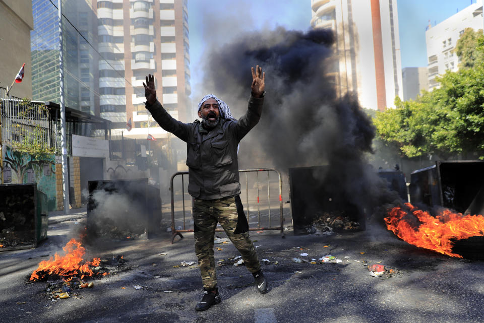 A man shouts slogans in front of burning tires and garbage containers set on fire to block a main road during a protest against the increase in prices of consumer goods and the crash of the local currency, in Beirut, Lebanon, Tuesday, March 16, 2021. Scattered protests broke out on Tuesday in different parts of the country after the Lebanese pound hit a new record low against the dollar on the black market. (AP Photo/Hussein Malla)