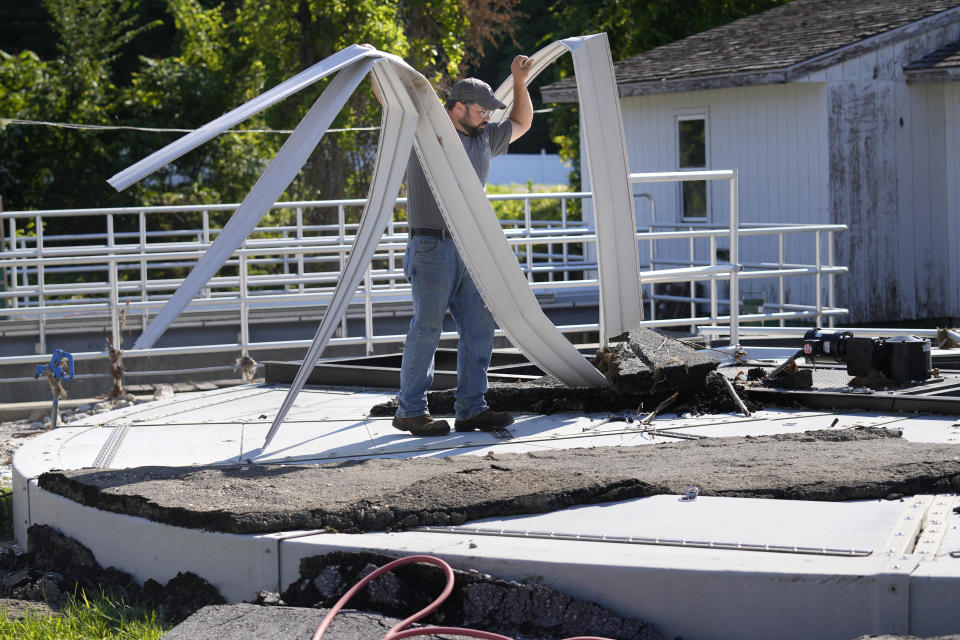 Elijah Lemieux, of the Vermont Rural Water Association, cleans up debris that was left by rising waters over the wastewater clarifier at the treatment plant following July flooding, Wednesday, Aug. 2, 2023, in Ludlow, Vt. Across the U.S., municipal water systems and sewage treatment plants are at increasing risk of damage from floods and sea-level rise brought on in part or even wholly by climate change. The storm that walloped Ludlow especially hard, damaging the picturesque ski town’s system for cleaning up sewage before it’s discharged into the Williams River. (AP Photo/Charles Krupa)
