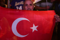 A supporter of the newly elected Turkish Cypriot leader Ersin Tatar holds a Turkish flag and celebrates, in the Turkish occupied area in the north part of the divided capital Nicosia, Cyprus, Sunday, Oct. 18, 2020. Ersin Tatar, a hardliner who favors even closer ties with Turkey and a tougher stance with rival Greek Cypriots in peace talks has defeated the leftist incumbent in the Turkish Cypriot leadership runoff. (AP Photo/Nedim Enginsoy)