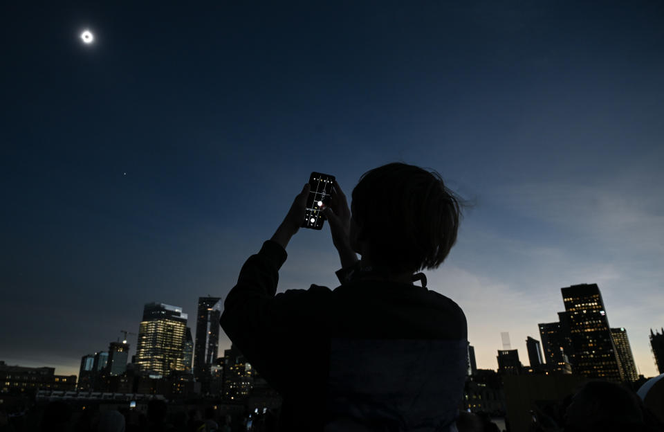 A person takes a photograph of the sun during totality as the moon passes between it and the earth resulting in a total solar eclipse, in Montreal, Monday, April 8, 2024. THE CANADIAN PRESS/Graham Hughes