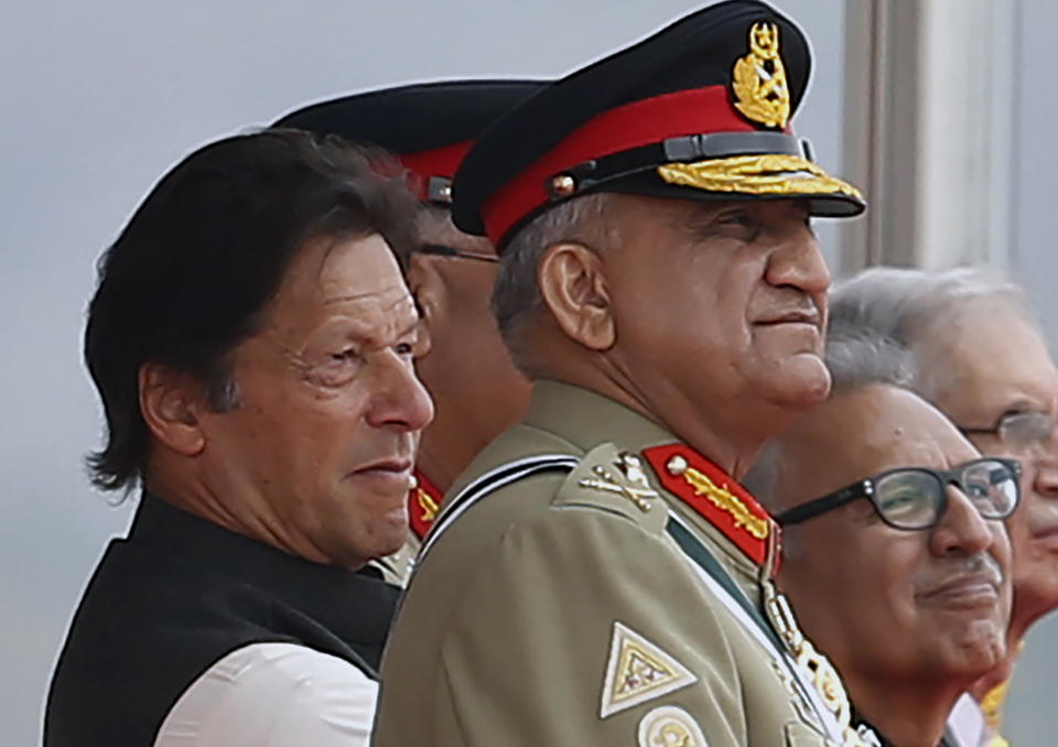 In this March 23, 2019 photo, Pakistan's Army Chief Gen. Qamar Javed Bajwa, center, watches a parade with Prime Minister Imran Khan, left, and President Arif Alvi, in Islamabad, Pakistan. Khan is keeping his powerful army chief in place for another three years, amid heightened tensions with India over Kashmir as well as the end of U.S.-Talban peace talks for neighboring Afghanistan. Khan postponed the retirement of Bajwa on Monday, Aug. 19, 2019. (AP Photo/Anjum Naveed)